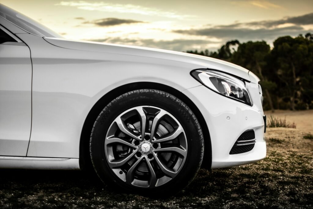 Close-up of a white car with stylish rims, captured outdoors in a serene setting.
