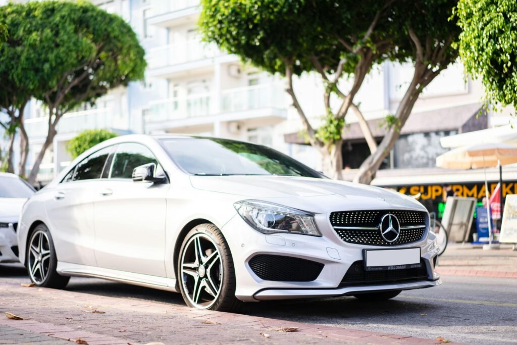 Elegant white Mercedes Benz car parked on a sunny urban street.